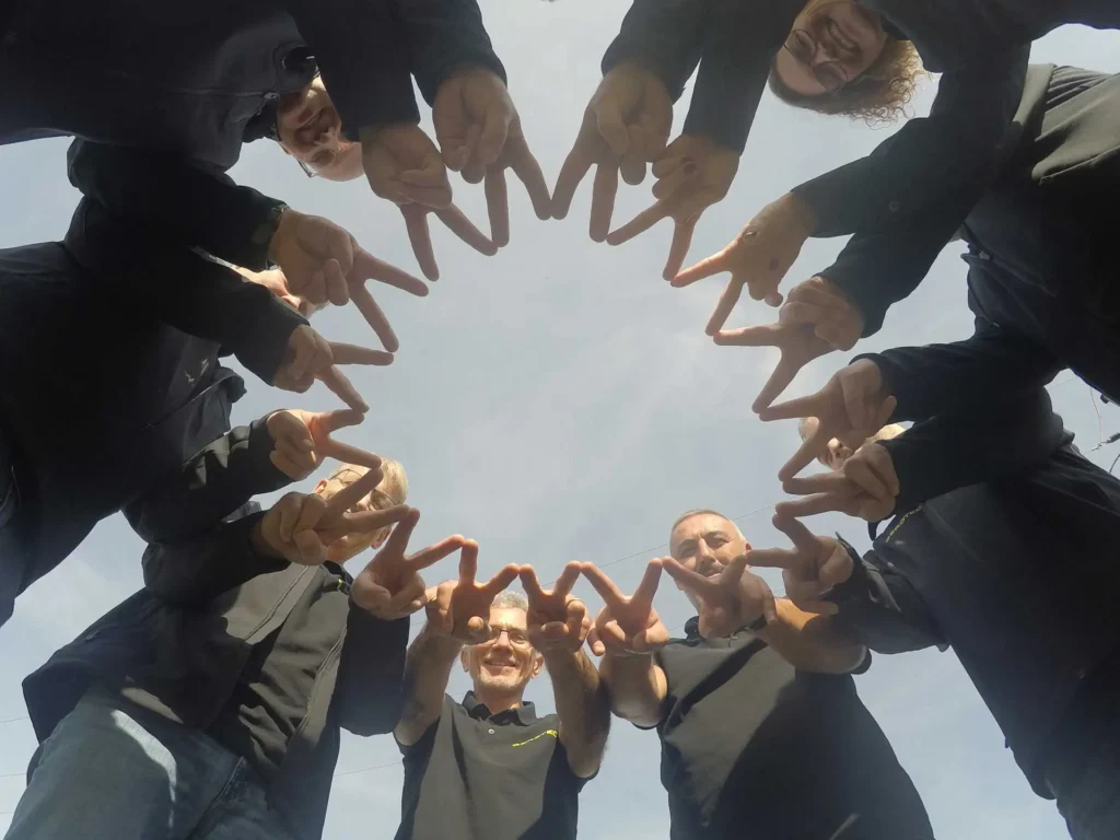 Das Gerotec-Team steht im Kreis und formt mit den Händen einen Stern, Blick von unten in den Himmel.